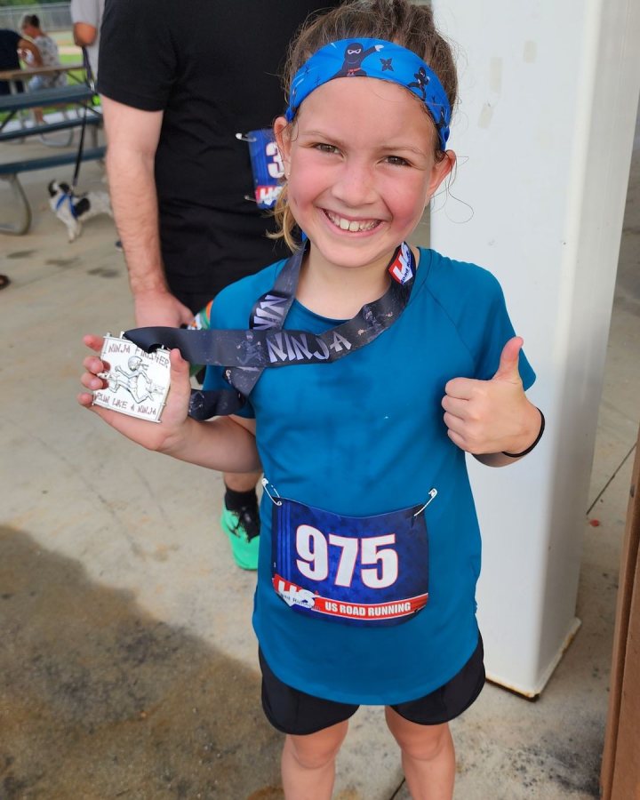 US Road Running race day photo with runners, walkers, finisher medals, and race staff