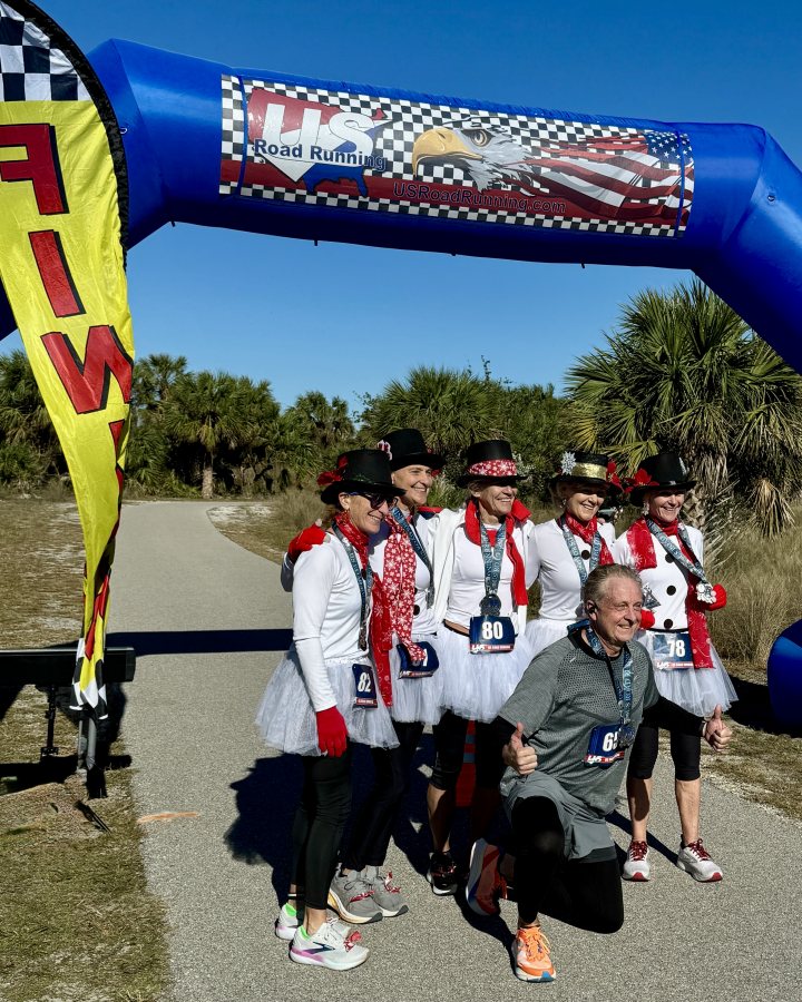 US Road Running race day photo with runners, walkers, finisher medals, and race staff
