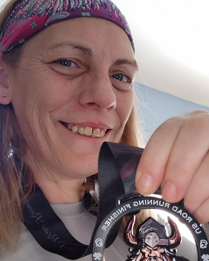 US Road Running race day photo with runners, walkers, finisher medals, and race staff