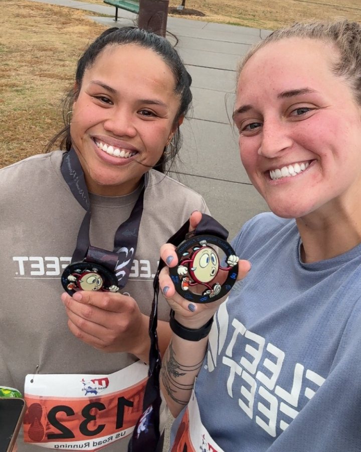 US Road Running race day photo with runners, walkers, finisher medals, and race staff